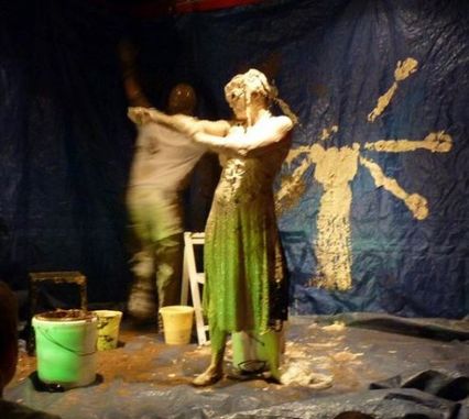 Alice Aucuit Artiste Céramiste, debout devant une toile sombre tendue avec une syloette à plusieurs bras