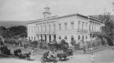 photo noir et blanc d'un grand bâtiment colonial blanc avec de nombreuses fenêtres et un clocheton