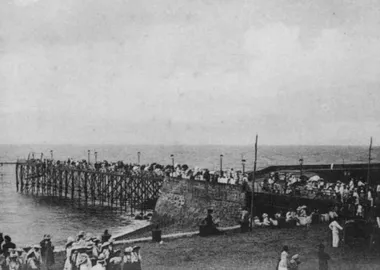 photo noir et blanc d'une jetée sur pilittis au dessus de la mer avec du monde autour