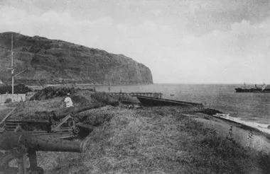 photo noir et blanc de la rade avec un canon au premier plan et une falaise au fond