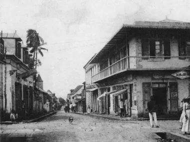 photo noir et blanc d'un croisement de deux rues ou les maisons d'angle ont des boutiques